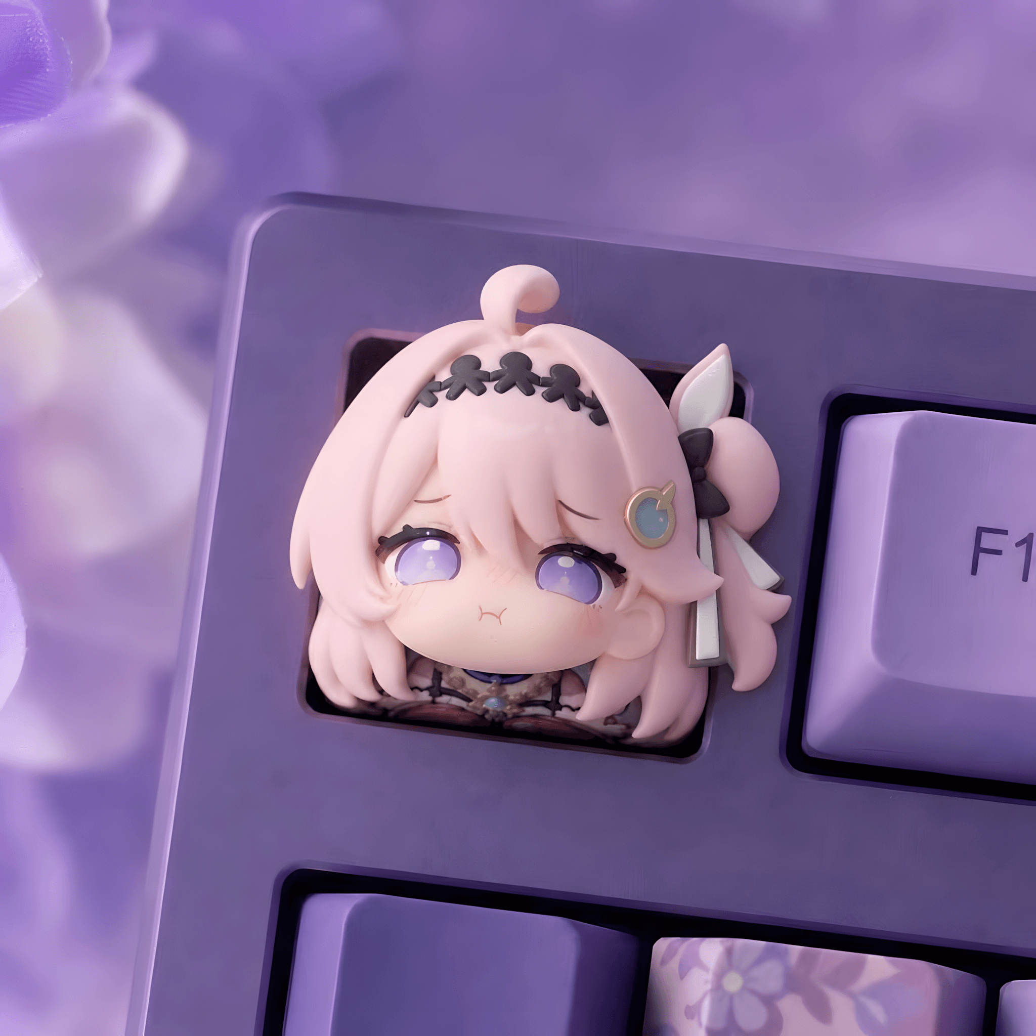 A cute chibi anime character keycap insert on a purple mechanical keyboard, featuring a pink-haired character with large purple eyes and a sad expression.